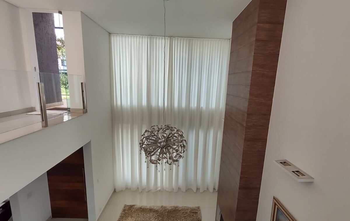 Cortina translúcida em sala com pé-direito duplo: a automação permite controlar a entrada de luz com um comando.