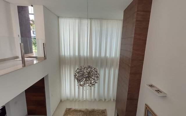 Cortina translúcida em sala com pé-direito duplo: a automação permite controlar a entrada de luz com um comando.